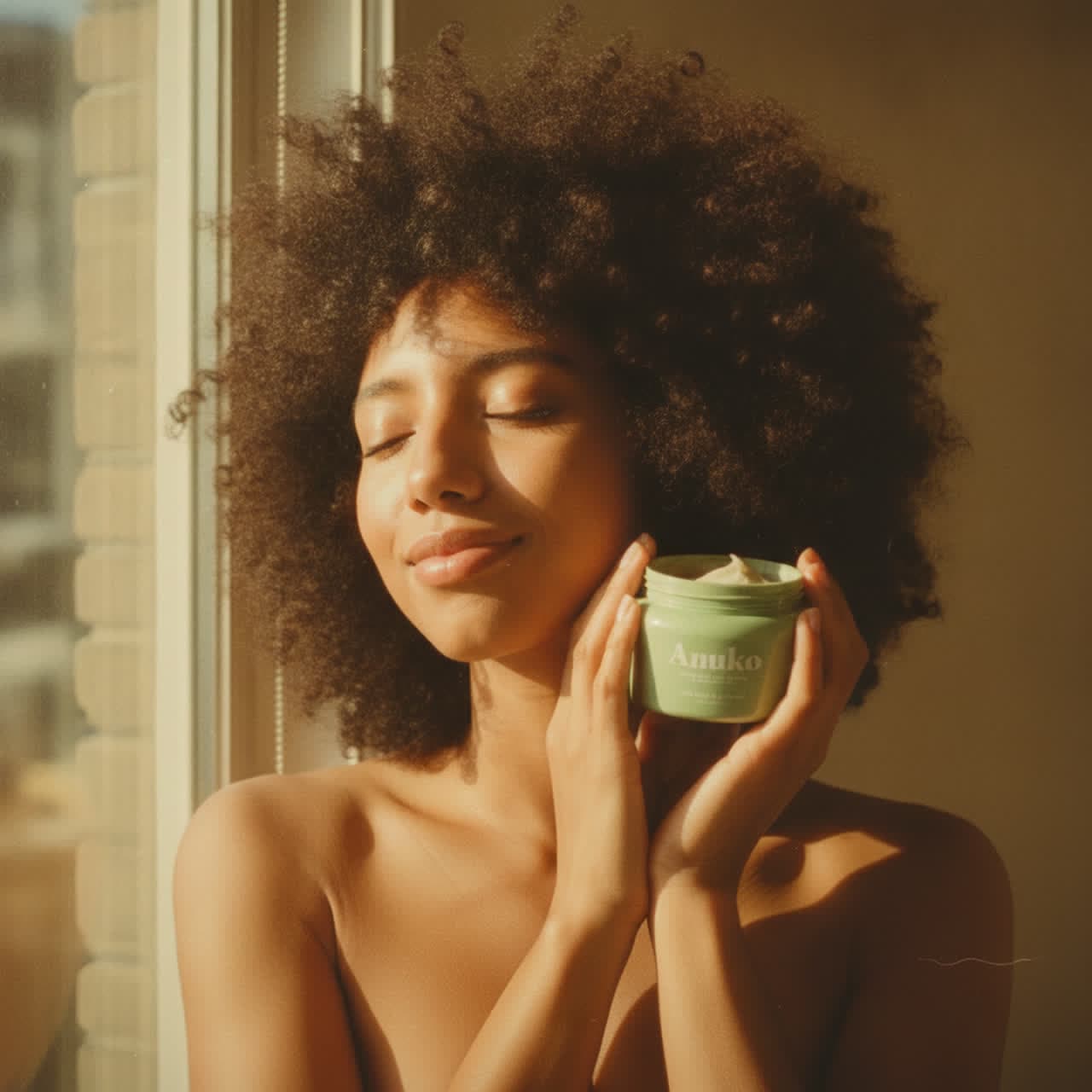 Holding the Anuko Nourishing Hair Butter in warm vintage light