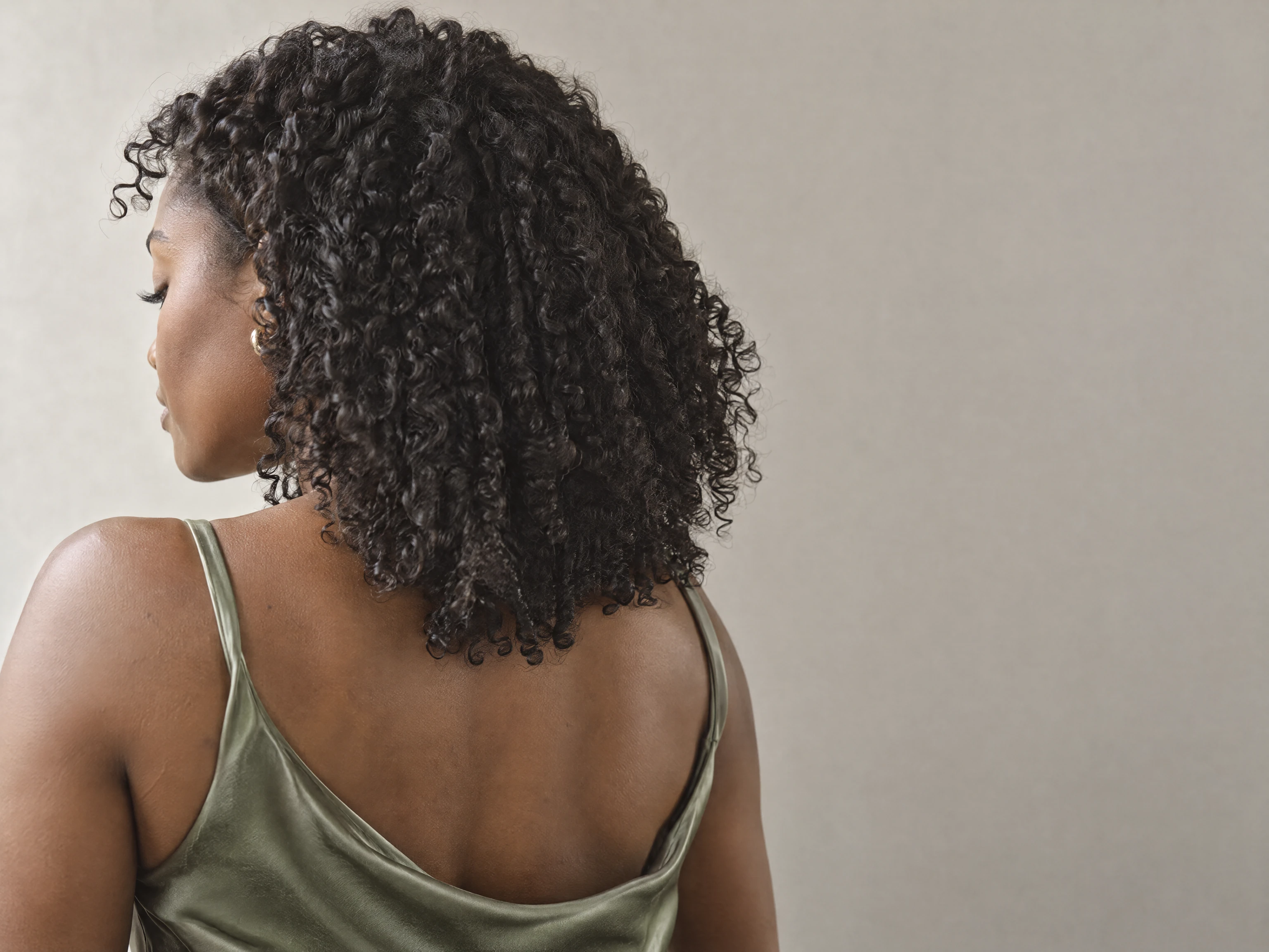 A woman seen from behind with defined, glossy coily curls