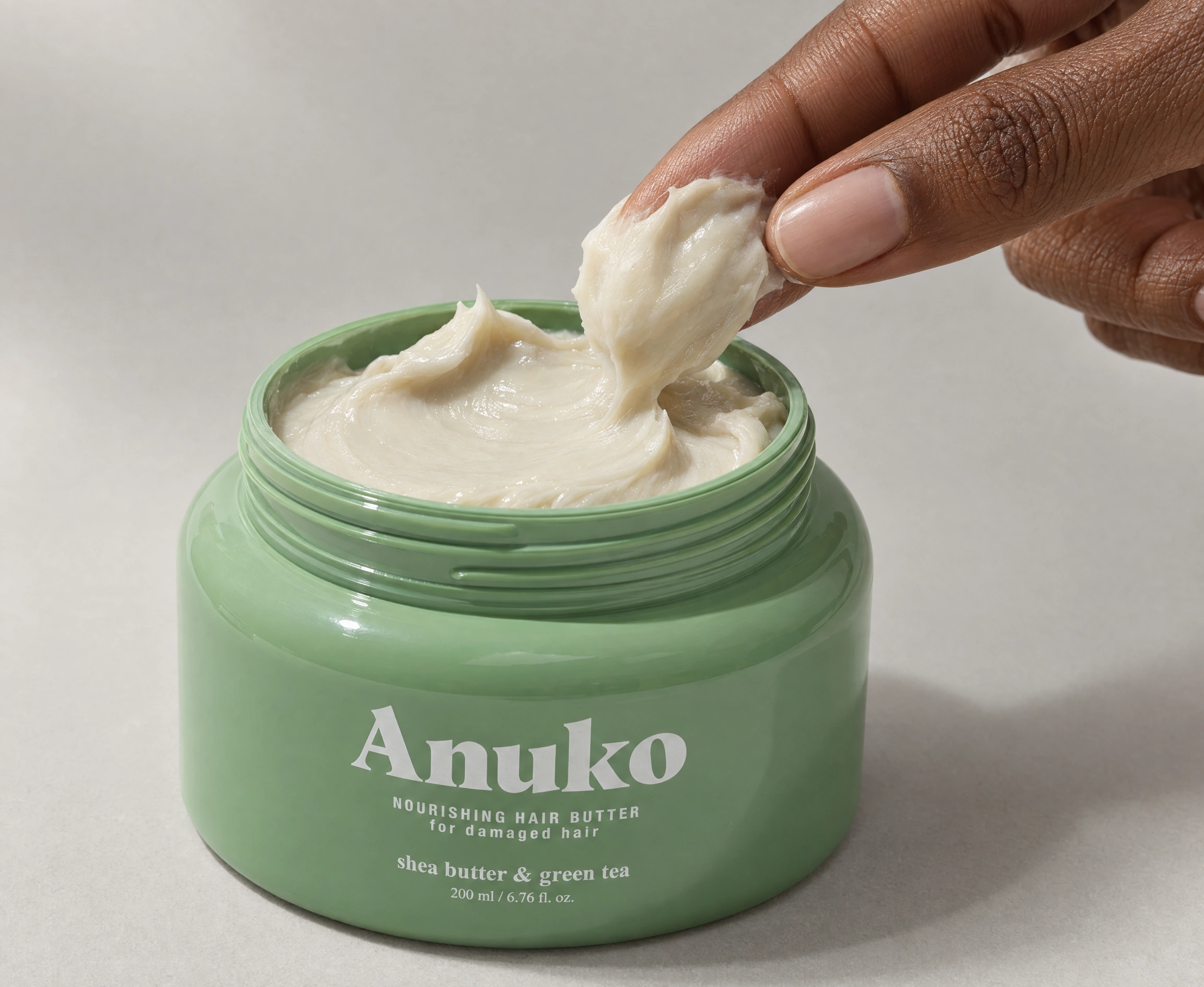 Fingertips scooping whipped Anuko Nourishing Hair Butter from the open jar